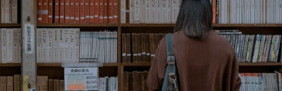 A woman infront of a shelf full of books.