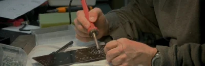 A man holding a soldering iron and repairing a PCB.